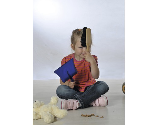 O fată stă pe podea și se joacă cu o farfurie și o mătură de mână.