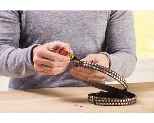 O persoană repară o curea cu ținte cu adeziv universal.