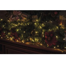 Șemineu decorativ cu decorațiuni de Crăciun, ghirlande luminoase, ramuri de brad, cadouri și conuri de pin