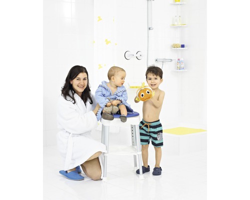 Scenă de baie cu o mamă, un copil pe un scaun de duș și un copil mai mare cu o jucărie de baie.