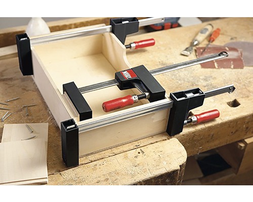 Cutie din lemn fixată cu cleme pe un banc de lucru