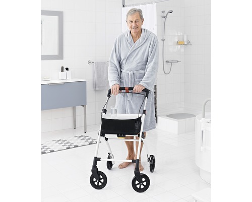 Un bărbat cu halat de baie și cadru de mers într-o baie.