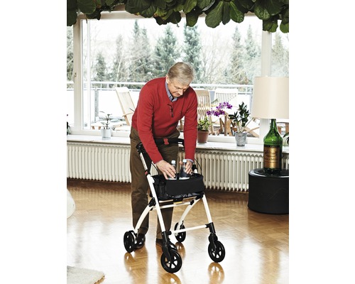 Bărbat folosind un rollator într-o sufragerie luminoasă.