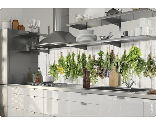 Scenă de bucătărie cu dulapuri albe, chiuvetă din oțel inoxidabil și motiv cu ierburi pe peretele din spate