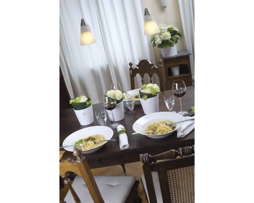 Masa de dining aranjată cu paste, flori și vin sub lămpi suspendate