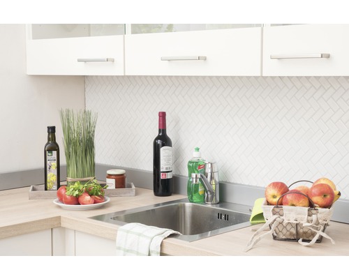 Scenă de bucătărie cu chiuvetă, robinet și diverse ustensile de bucătărie pe blat.