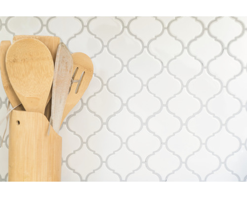 Utensile de bucătărie din lemn în suport în fața unui perete cu model