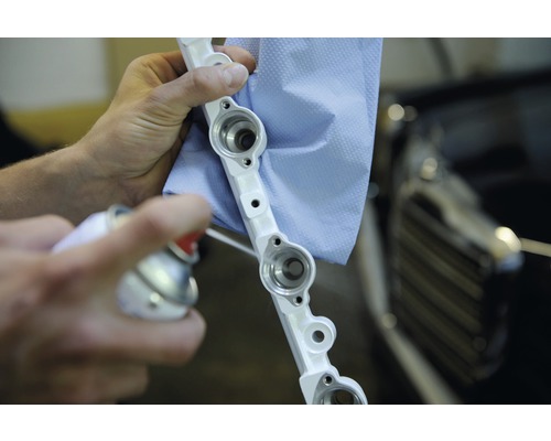 Curățarea unei galerii de distribuție a combustibilului cu un spray de curățare și o cârpă