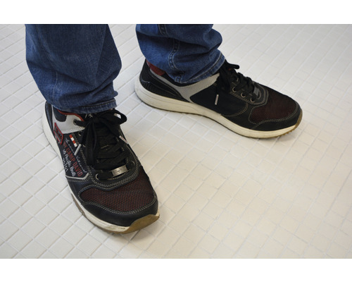 O pereche de pantofi cu șireturi din material textil și material sintetic pe piciorul unei persoane.