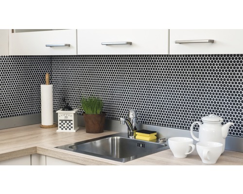 Scenă de bucătărie cu chiuvetă, robinet, plăci de mozaic și ustensile de bucătărie pe blat.