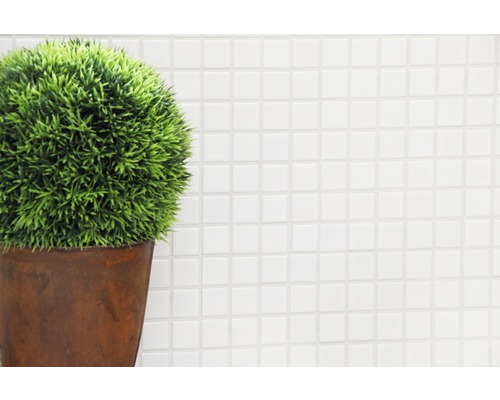 Plantă artificială decorativă într-un ghiveci în fața unui fundal alb cu mozaic