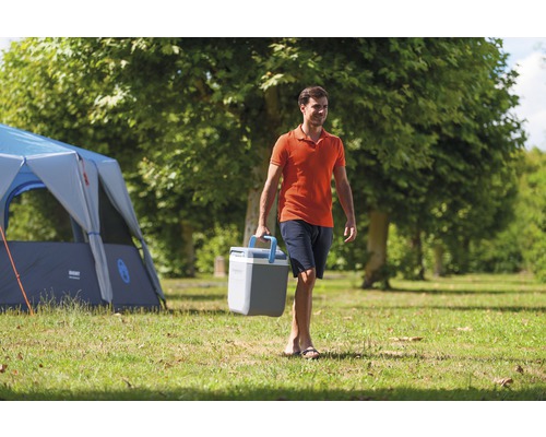 Bărbat care poartă cutie frigorifică lângă cort pe gazon