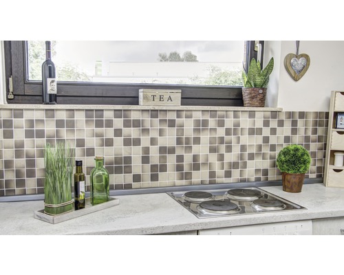 Scenă de bucătărie cu faianță mozaic, plită și elemente decorative.