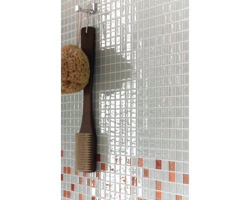 Prim-plan cu un perete cu gresie mozaic, un burete de baie și o perie