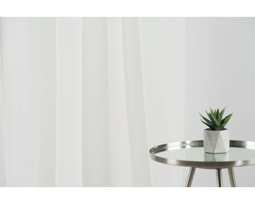 Perdele decorative și o plantă mică pe o măsuță laterală creează o atmosferă luminoasă în cameră.