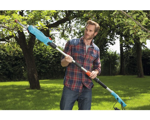 Un bărbat taie un copac cu un fierăstrău de crengi înalte