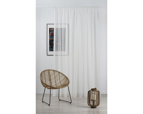 Interior luminos cu perdea albă, scaun de ratan și lanternă