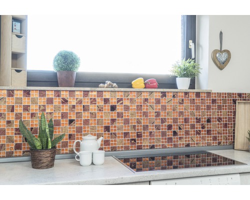Scenă de bucătărie cu perete cu plăci de mozaic, plante și ustensile de bucătărie pe blat.