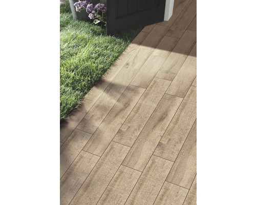 Montarea plăcilor de pardoseală cu aspect de lemn în exterior, lângă o zonă de gazon