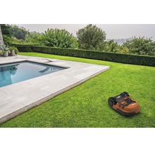 Robot de tuns iarba pe gazon lângă o piscină