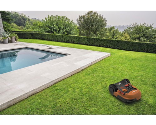 Robot de tuns iarba pe gazon lângă o piscină