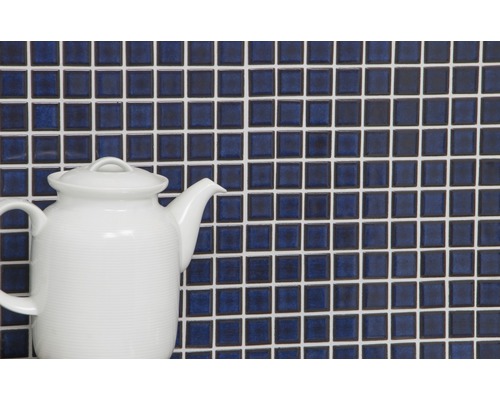 Perete din plăci de mozaic cu rosturi albe și un ceainic alb