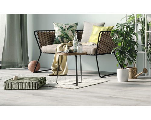 Scenă de living cu canapea, masă, perne și plante pentru o atmosferă confortabilă.