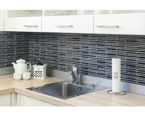 Scenă de bucătărie cu chiuvetă, robinet, blat, veselă și ustensile de bucătărie în fața unui perete cu mozaic negru