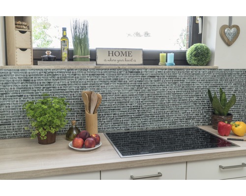 Scenă de bucătărie cu perete din mozaic, plită și ustensile de bucătărie pe un blat.