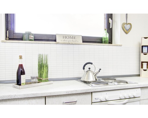 Scenă de bucătărie cu plită, ceainic, sticlă, pahar și elemente decorative.