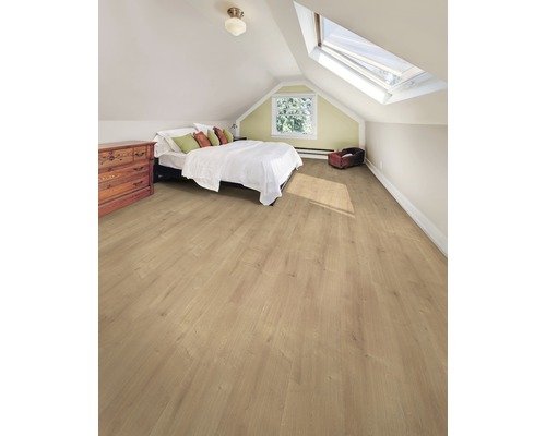 Cameră luminoasă la mansardă cu podea laminată, pat, comodă și fereastră de mansardă.