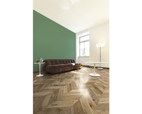 Cameră de zi cu canapea maro, podea din lemn cu model herringbone și perete verde