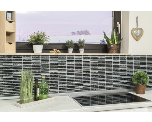 Scenă de bucătărie cu plăci de mozaic pe perete, plante și ustensile de bucătărie pe blatul de lucru.