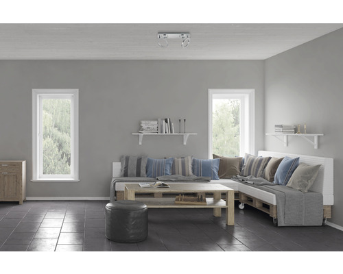 Cameră de zi cu fereastră, mobilă din lemn, canapea din paleți, măsuță laterală și bibliotecă.