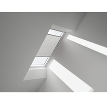 Fereastră de mansardă cu plissee într-o cameră luminoasă