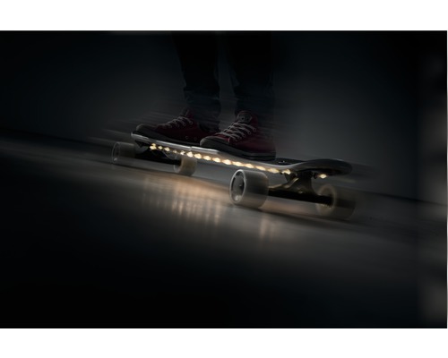 Persoană pe un skateboard cu iluminare LED în mișcare.