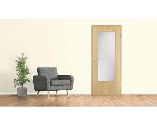Ușă interioară deschisă la culoare cu inserție de sticlă lângă un fotoliu și o plantă de apartament