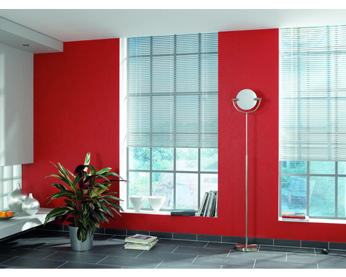 Cameră luminoasă cu două ferestre echipate cu jaluzele, perete roșu și lampadar