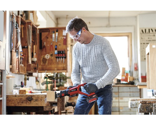 Bărbat taie lemn cu un fierăstrău sabie cu acumulator Einhell într-un atelier