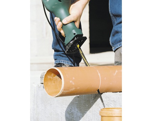 O persoană taie o țeavă cu un ferăstrău vertical.