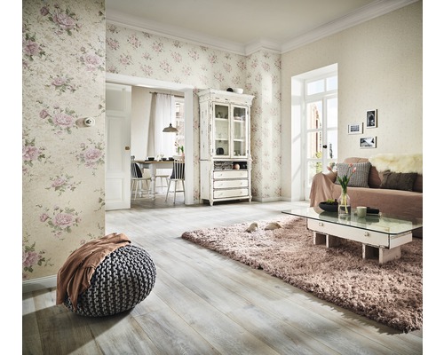 Cameră de zi cu tapet floral, canapea, covor și podea din lemn pentru o ambianță luminoasă.