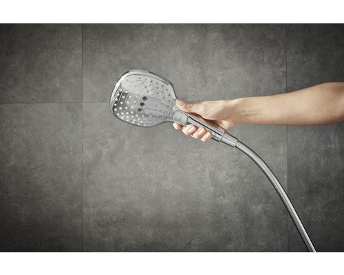 Mână care ține o pară de duș cu furtun.