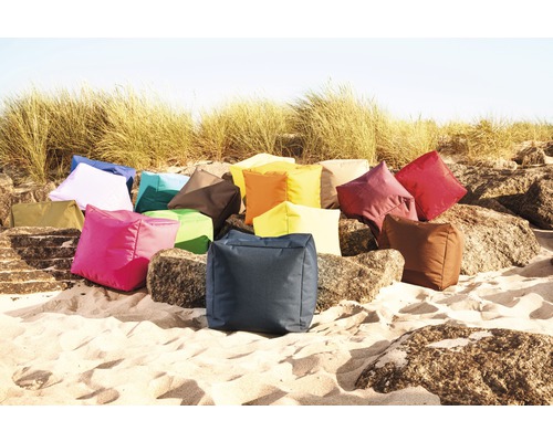 O colecție de perne de șezut pătrate de diferite culori pe nisip și pietre.