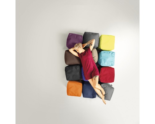 Femeie se odihnește pe un aranjament de cuburi de șezut în diferite culori