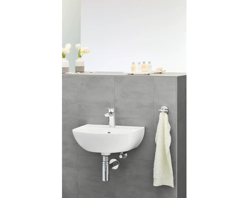 Chiuvetă suspendată în baie cu robinet, prosop și articole de toaletă