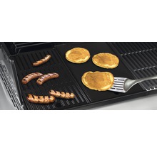 Grătar cu cârnați și clătite pe o placă de grătar cu o spatulă