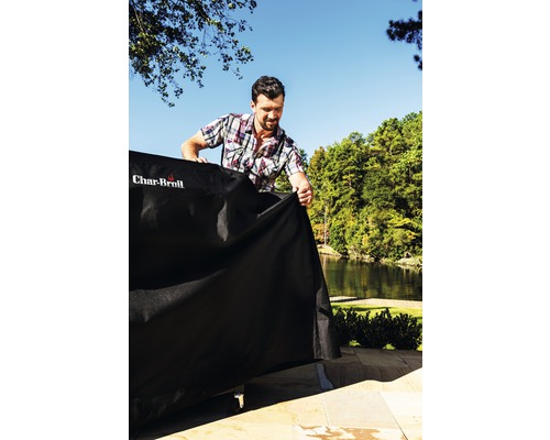 Bărbat așază o husă de protecție peste un grătar în aer liber cu logo-ul Char-Broil