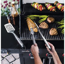 Persoană care grătar fripturi, sparanghel și frigărui de legume pe un grătar cu ustensile de grătar și sosuri