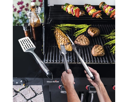 Persoană care grătar fripturi, sparanghel și frigărui de legume pe un grătar cu ustensile de grătar și sosuri