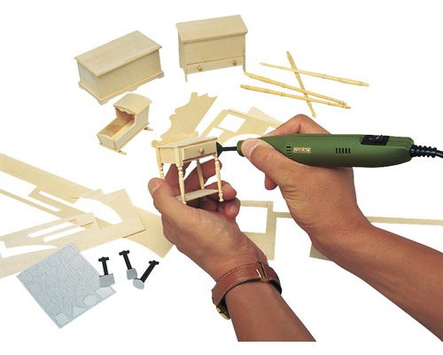 Persoană care lucrează la mobilă în miniatură cu o mașină de șlefuit. În fundal sunt vizibile alte piese de mobilier și unelte în miniatură.